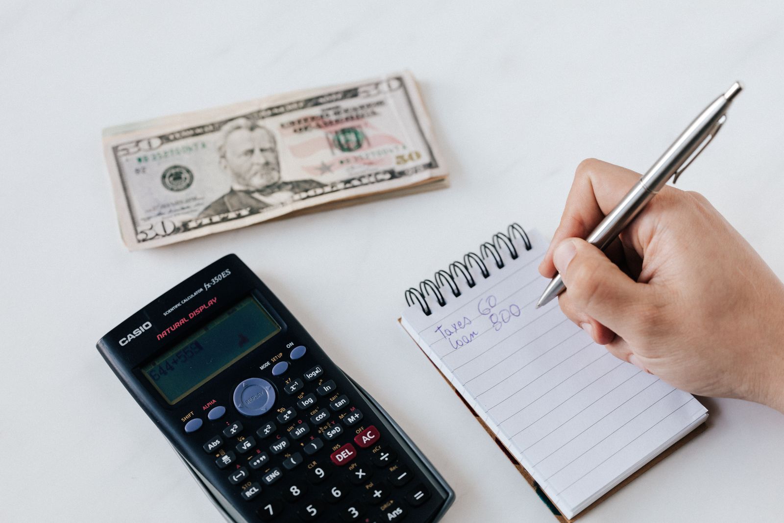 Bookkeeper using a calculator and notepad to record business transactions